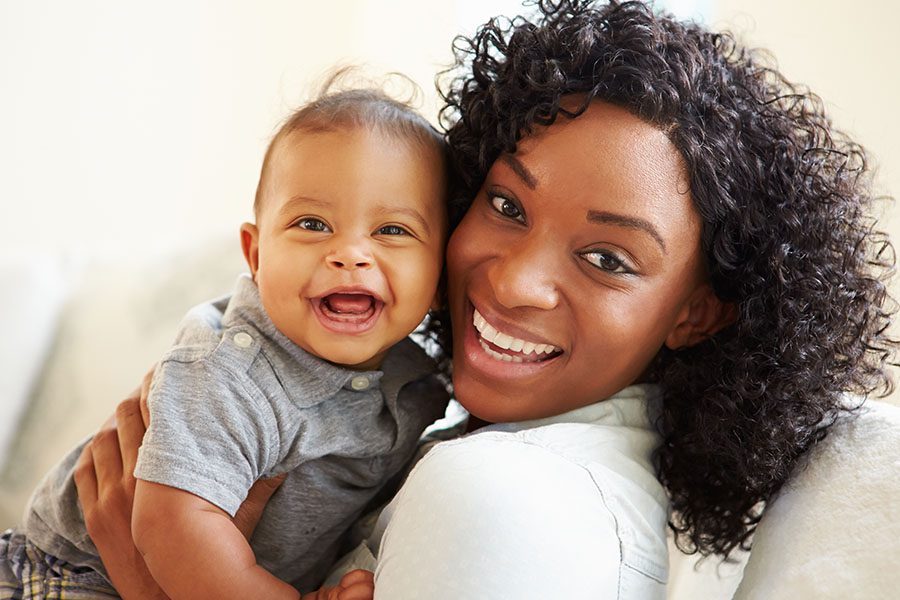 Group Voluntary Supplemental Life Insurance - Closeup View of Smiling Mother Playing with Baby Son at Home