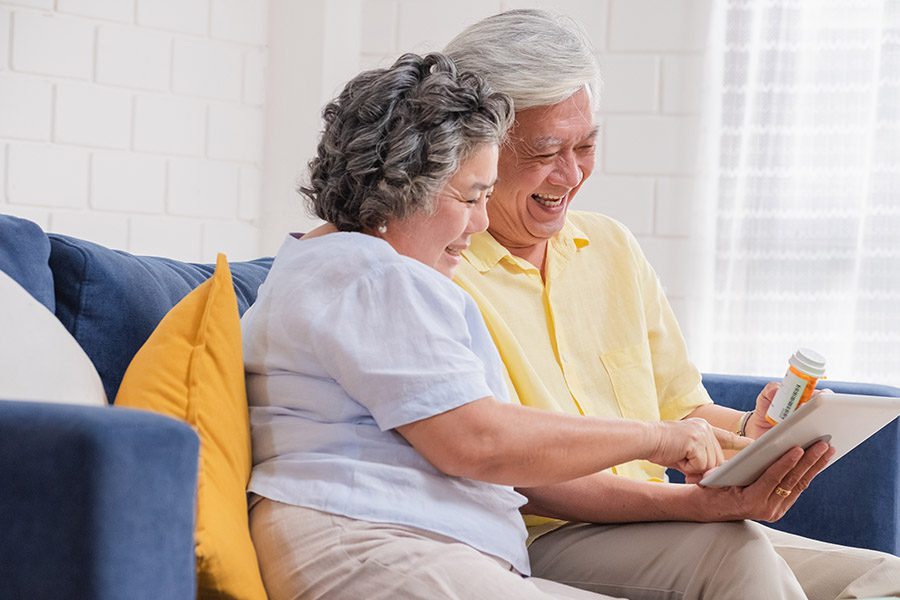 Medicare Part D Plan - Couple Use a Tablet to Video Conference with Their Doctor about Prescription While Sitting on Sofa at Home