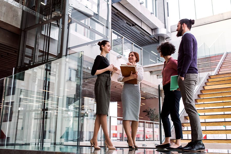 Contact - Group of Young Business People Standing near a Staircase and Talking